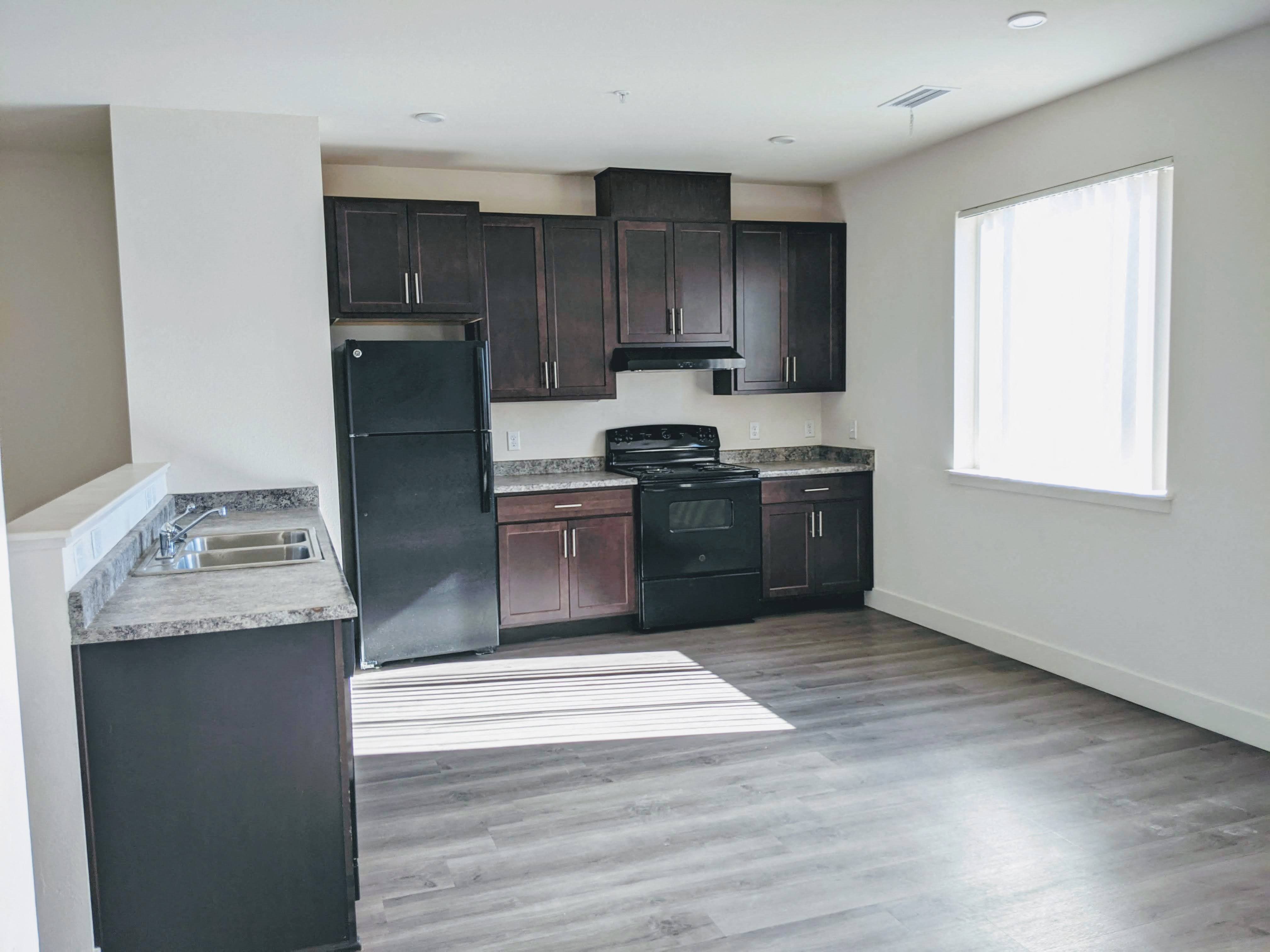 a kitchen with a sink, refrigerator, stove,  cabinets, and window